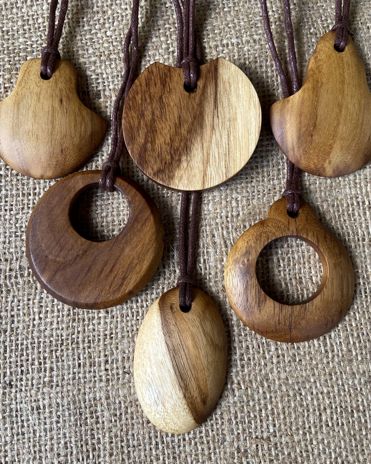 Hand-carved wooden pendants on a burlap surface