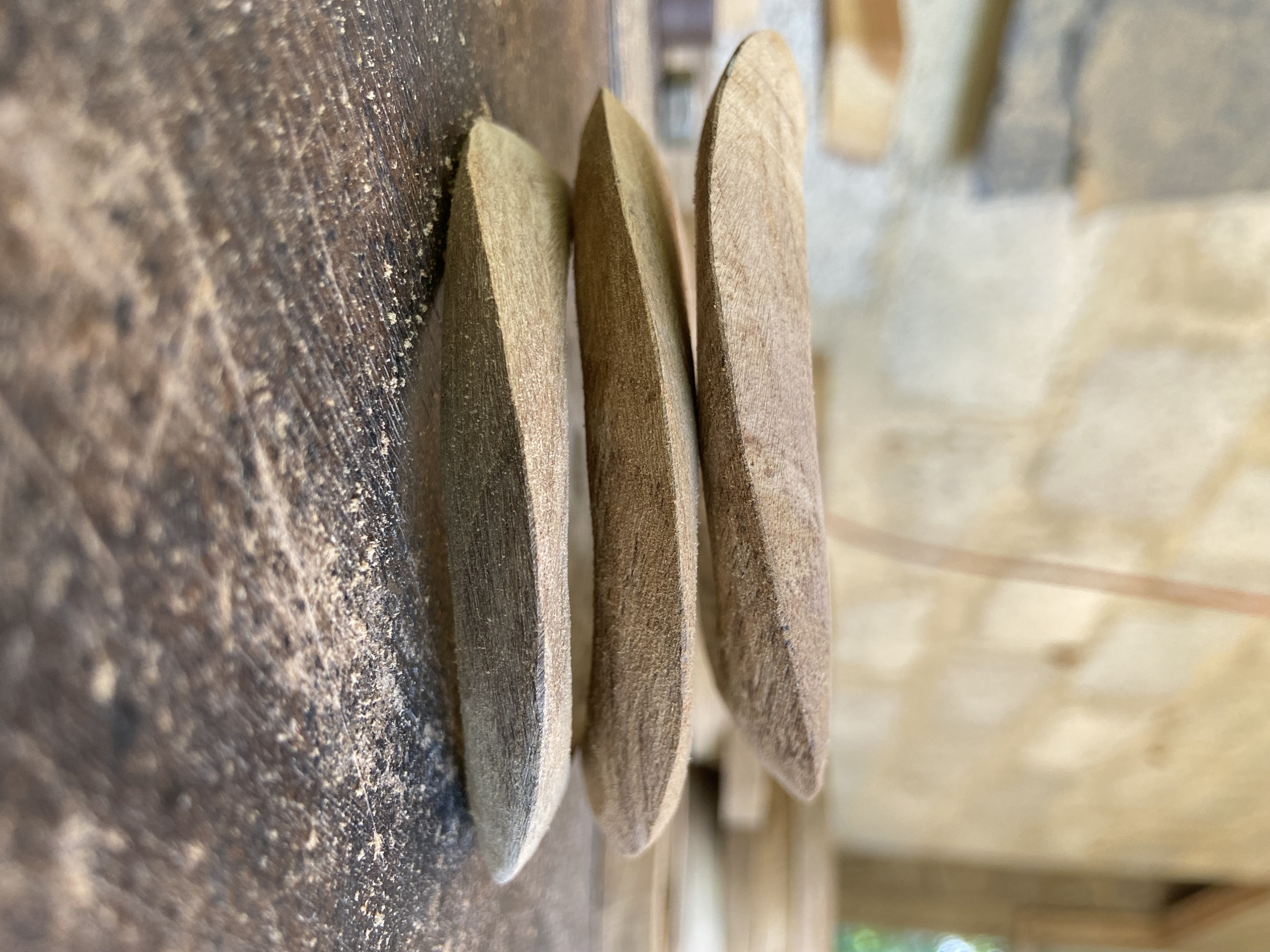Three smooth wooden pendant forms stacked on the bench