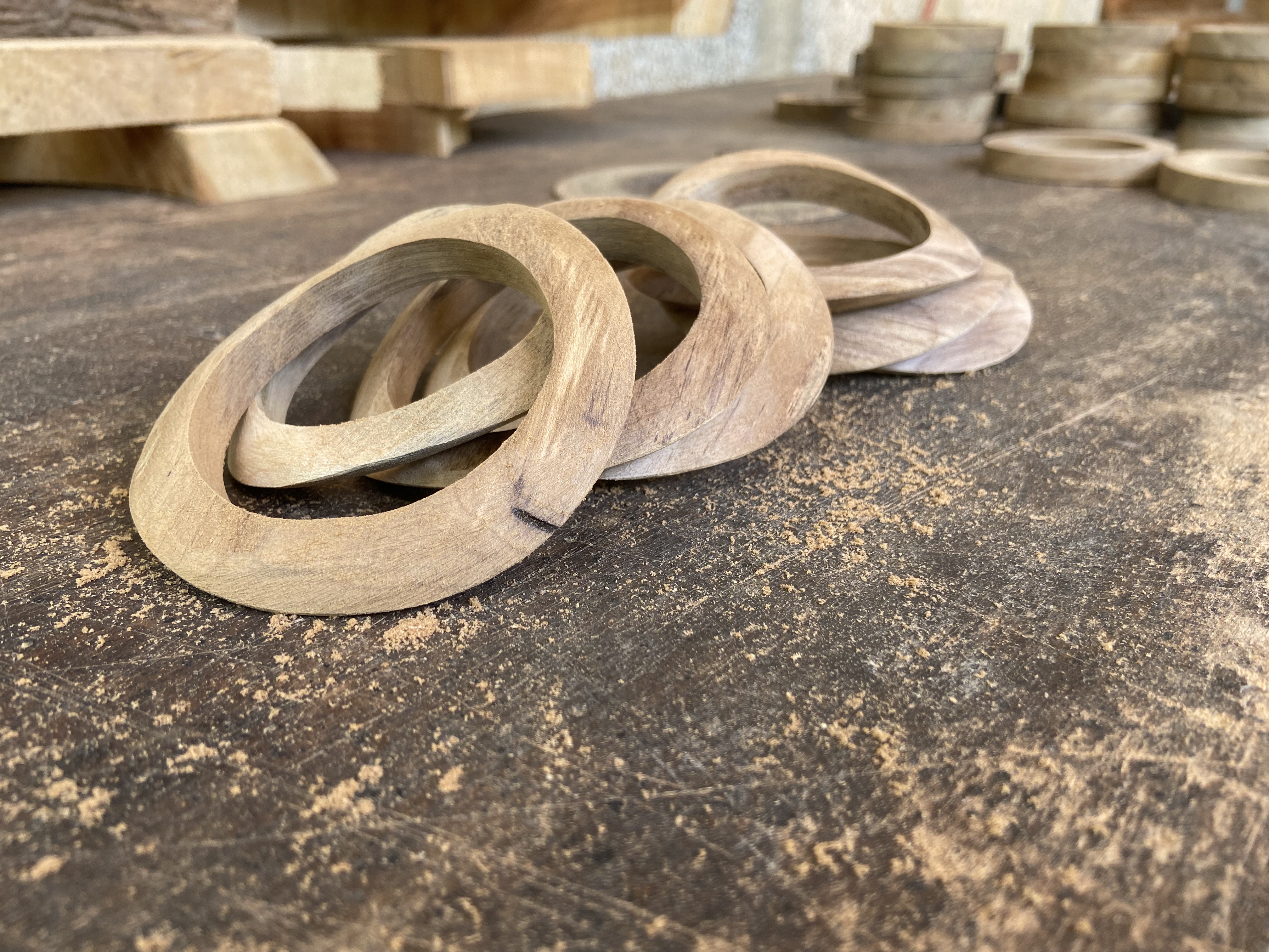 Carved wooden bangles resting on the bench in varied stages of finish