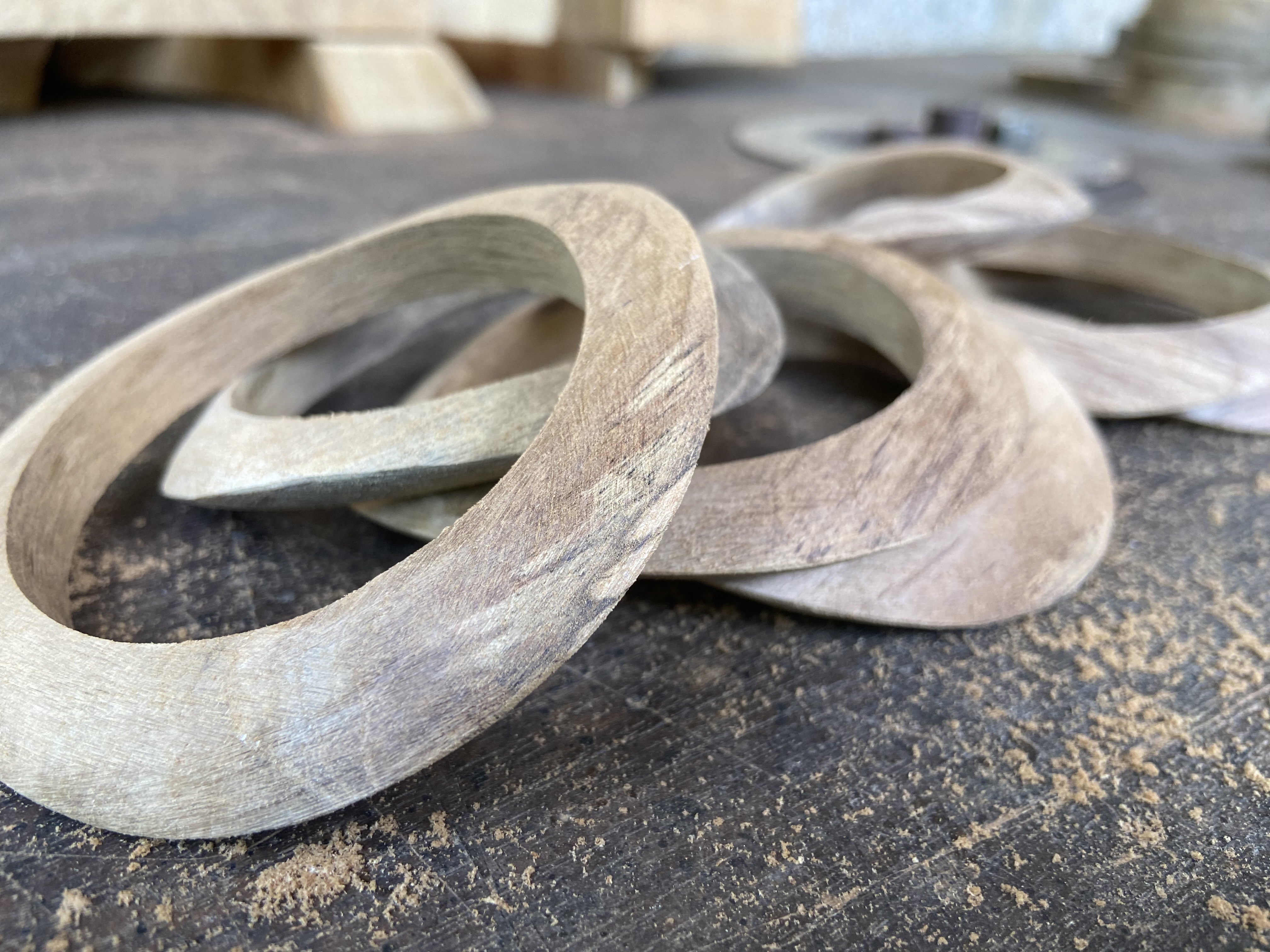 Wooden bangles in mid-carving, showing curved profiles and soft grain