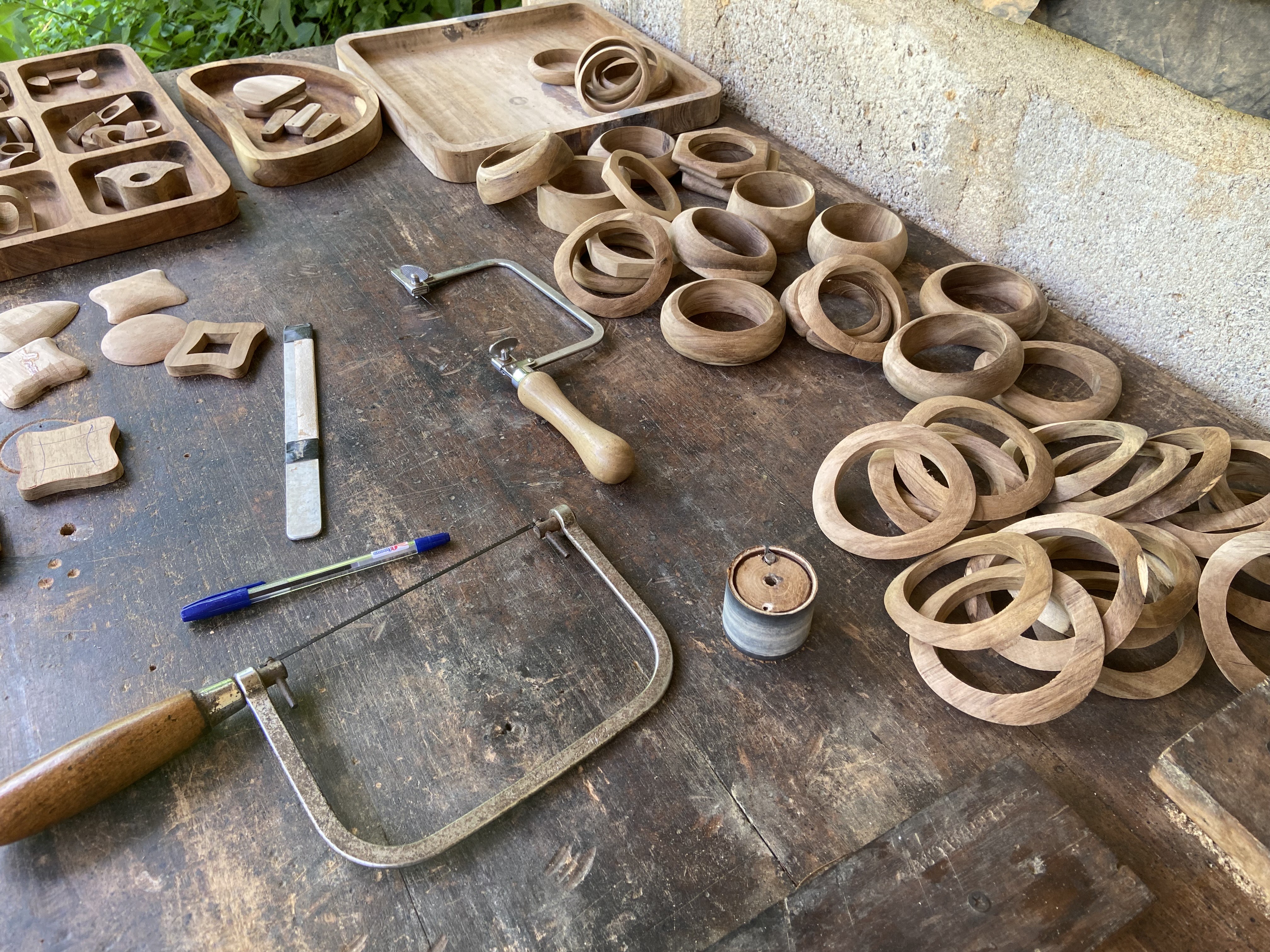 Wooden jewellery blanks and finished shapes across a workshop table