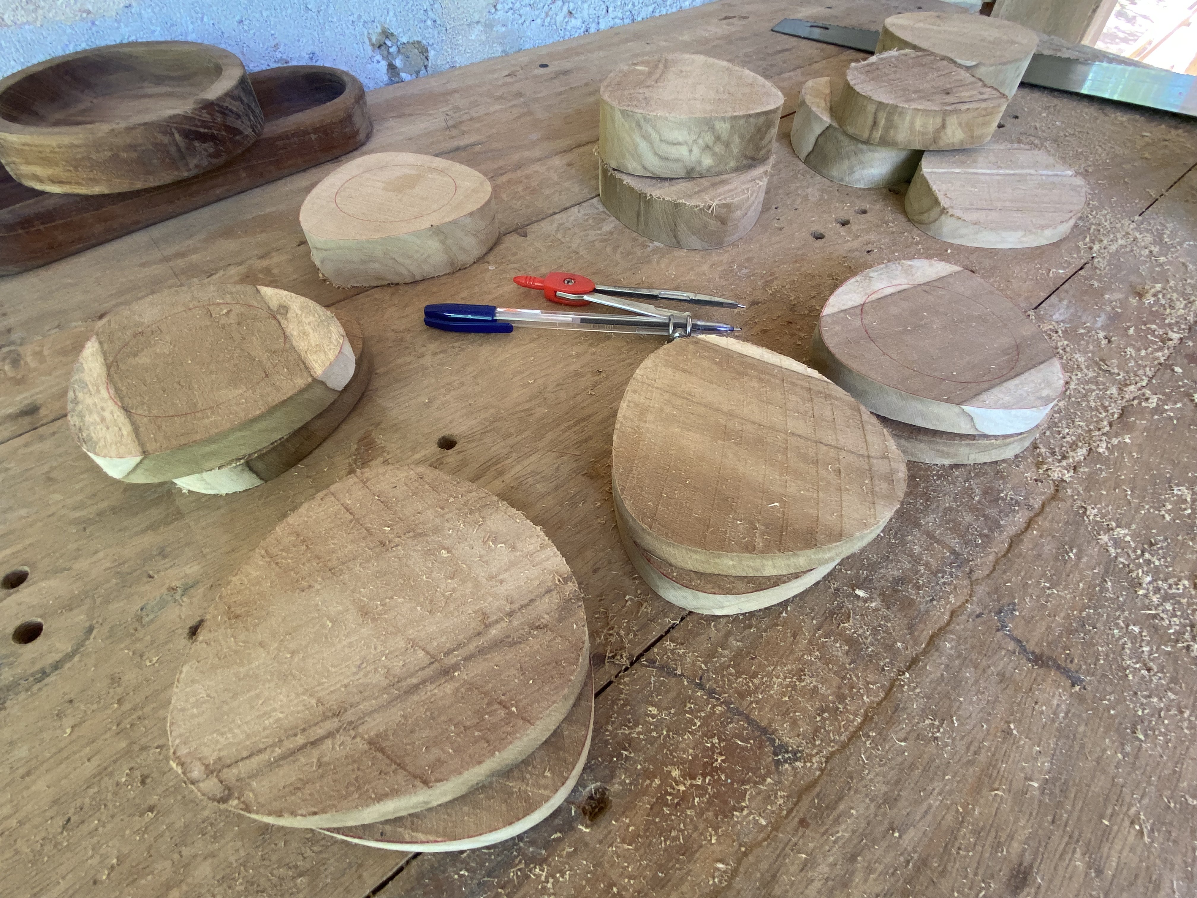 Round teak blanks on the workbench, marked with concentric compass circles